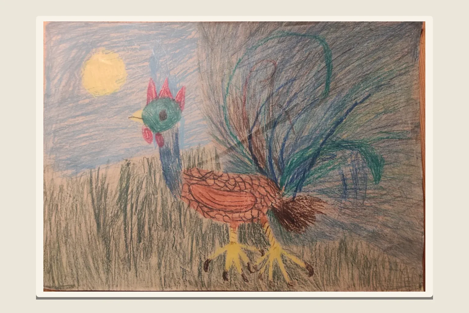 A child's crayon drawing of a rooster in tall grass under a yellow sun